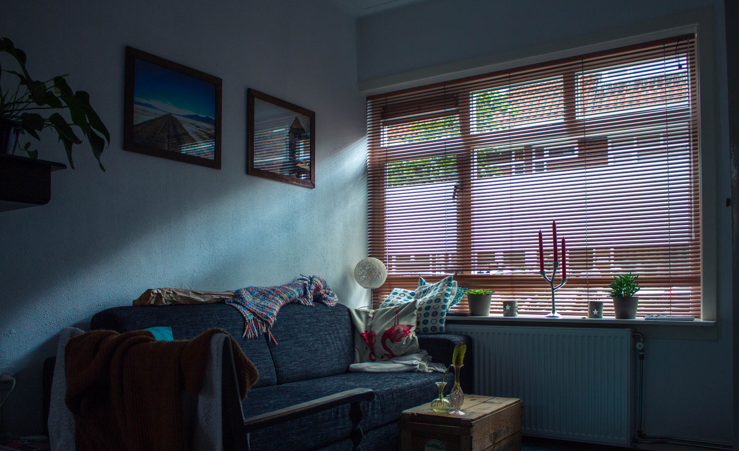 a couch in an apartment living room shaded by window blinds